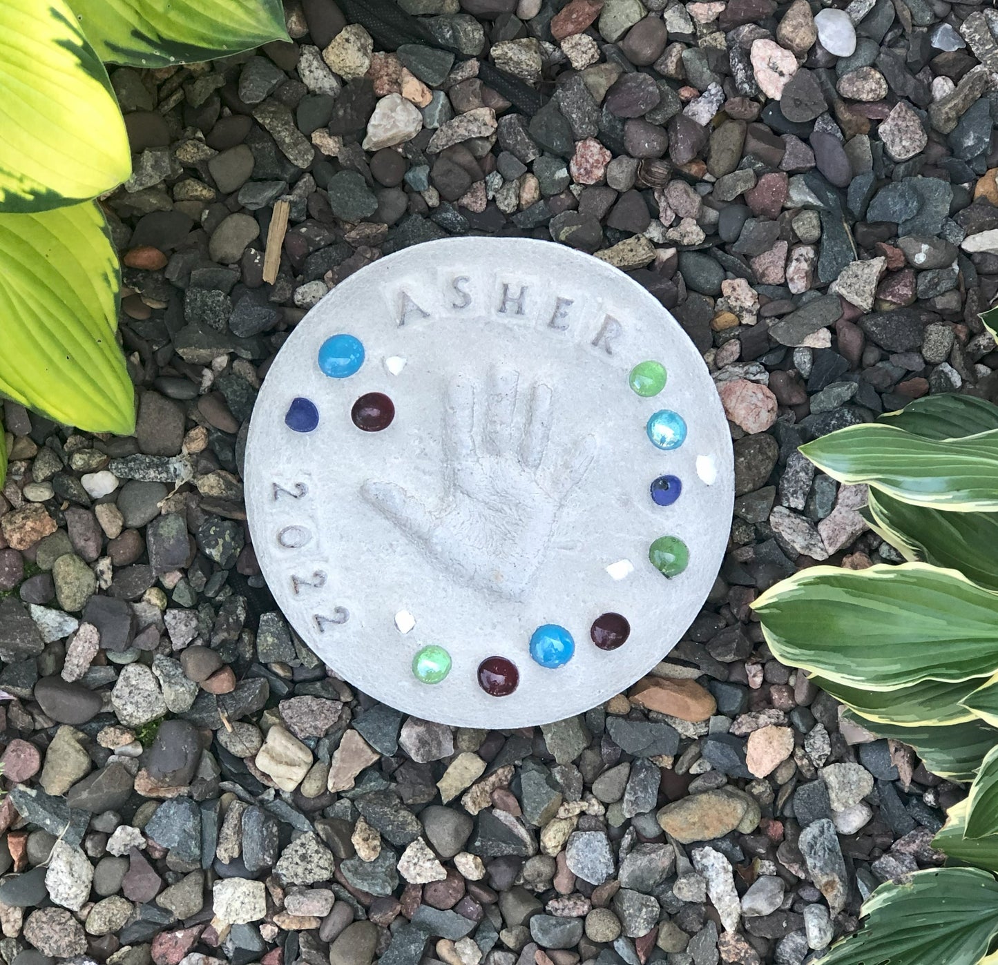 Grey round stepping stone kit displayed in raised garden bed