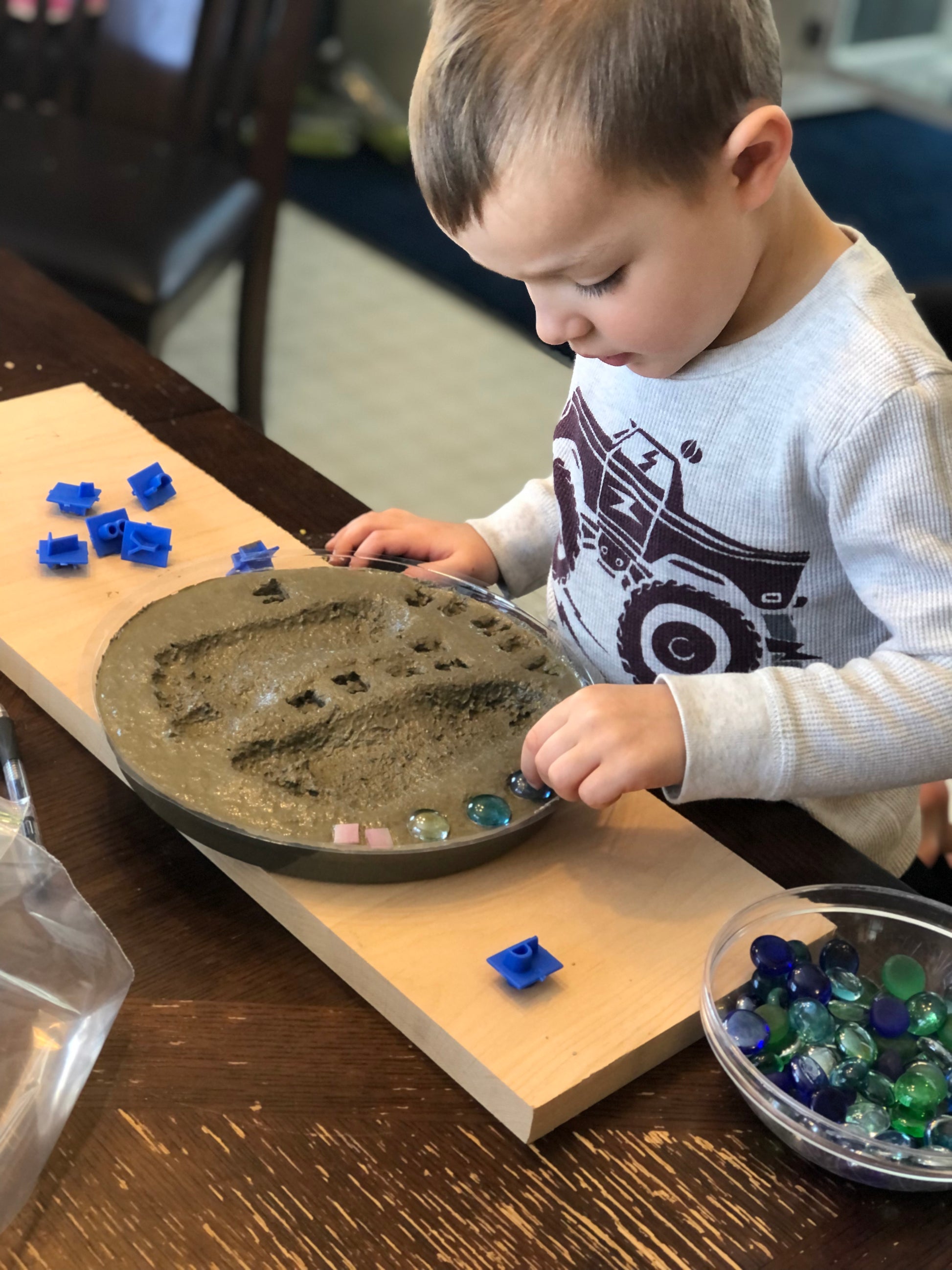 Child decorating his footprint stepping stone kit with mosaic glass gems. Children love making these easy to d kits!