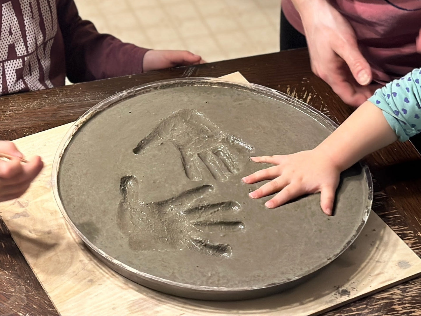 Make your own cement hand or foot print. DIY Kit Stepping Stone. This shows a child's hand being pressed into the wet concrete. Press the hand in deep to give the stone a great look once dry. Kid's may need help from parents when pushing hand down.