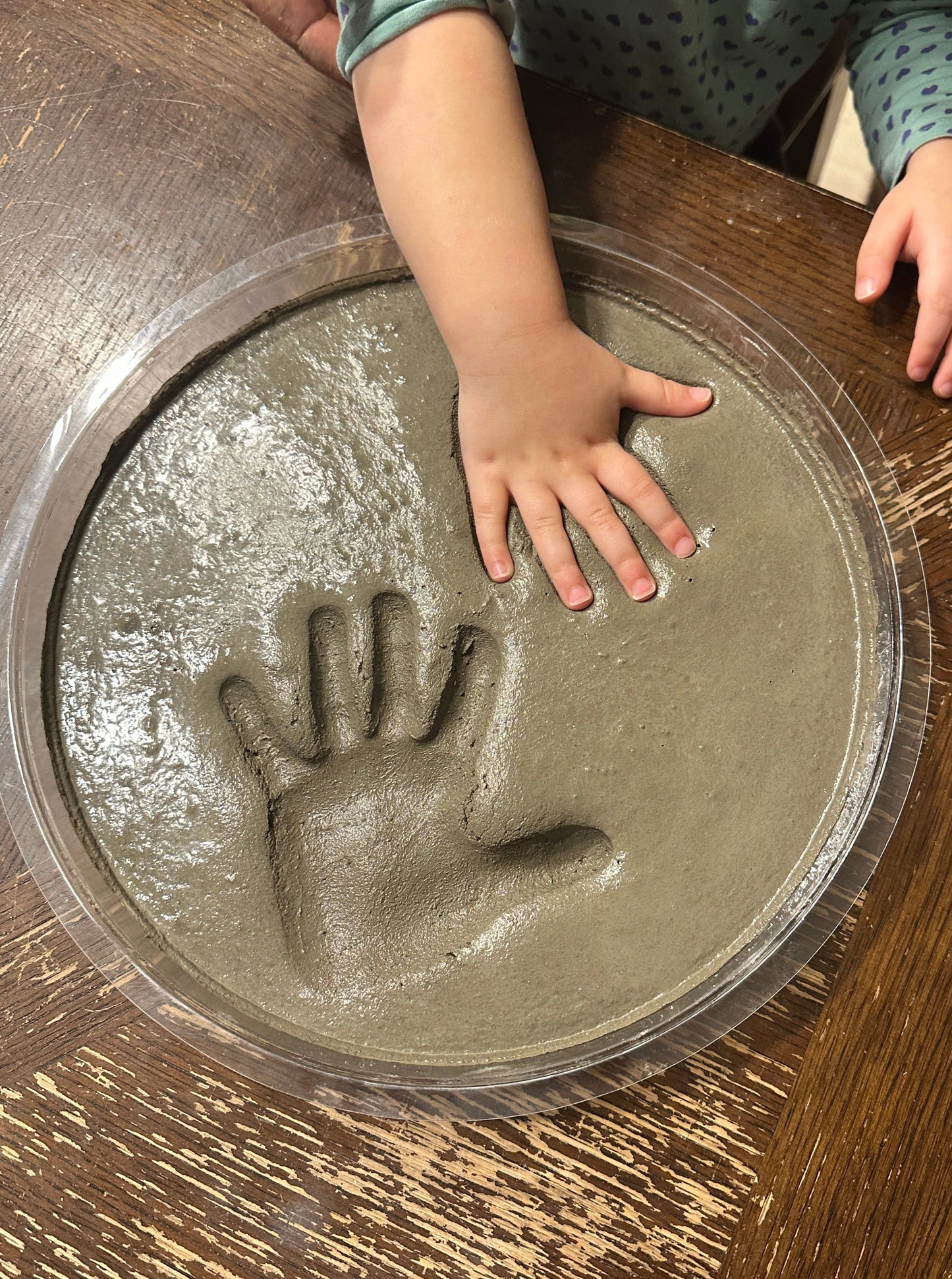 Make your own cement hand or foot print. DIY Kit Stepping Stone. This shows a child's hand being pressed into the wet concrete. Press the hand in deep to give the stone a great look once dry. Kid's may need help from parents when pushing hand down.