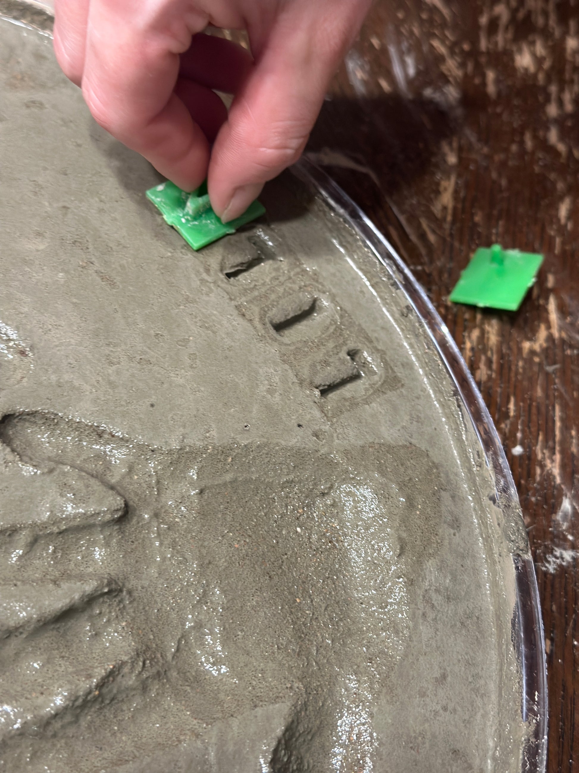 Close up image of the cement stamp set being used.  Here the child's name is being stamped into the concrete. You can add names and the year it was made to make a great memory stone for years to come! 